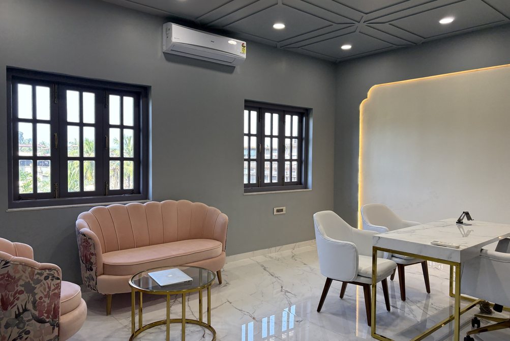 Modern grey-and-gold office cabin with pink sofa, marble table, and geometric moulding